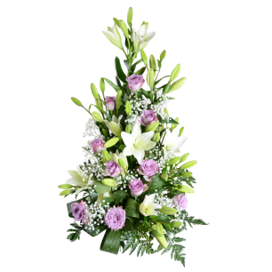 En blomsterarrangemang med vita liljor, lila rosor och små vita blommor omgivna av gröna blad.